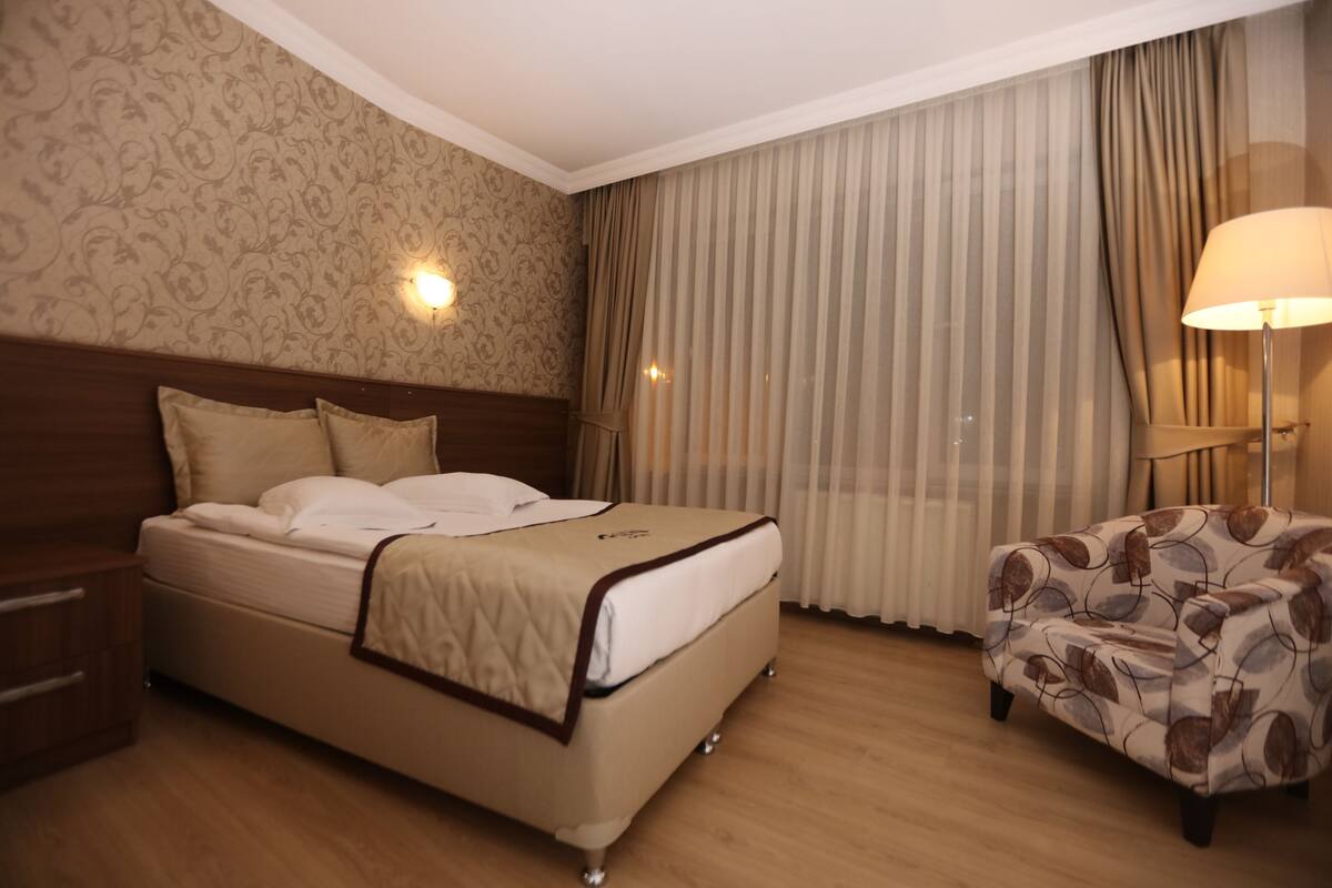 Ein Hotelzimmer mit einem Bett, einem Nachttisch, einem Stuhl und einer Lampe.