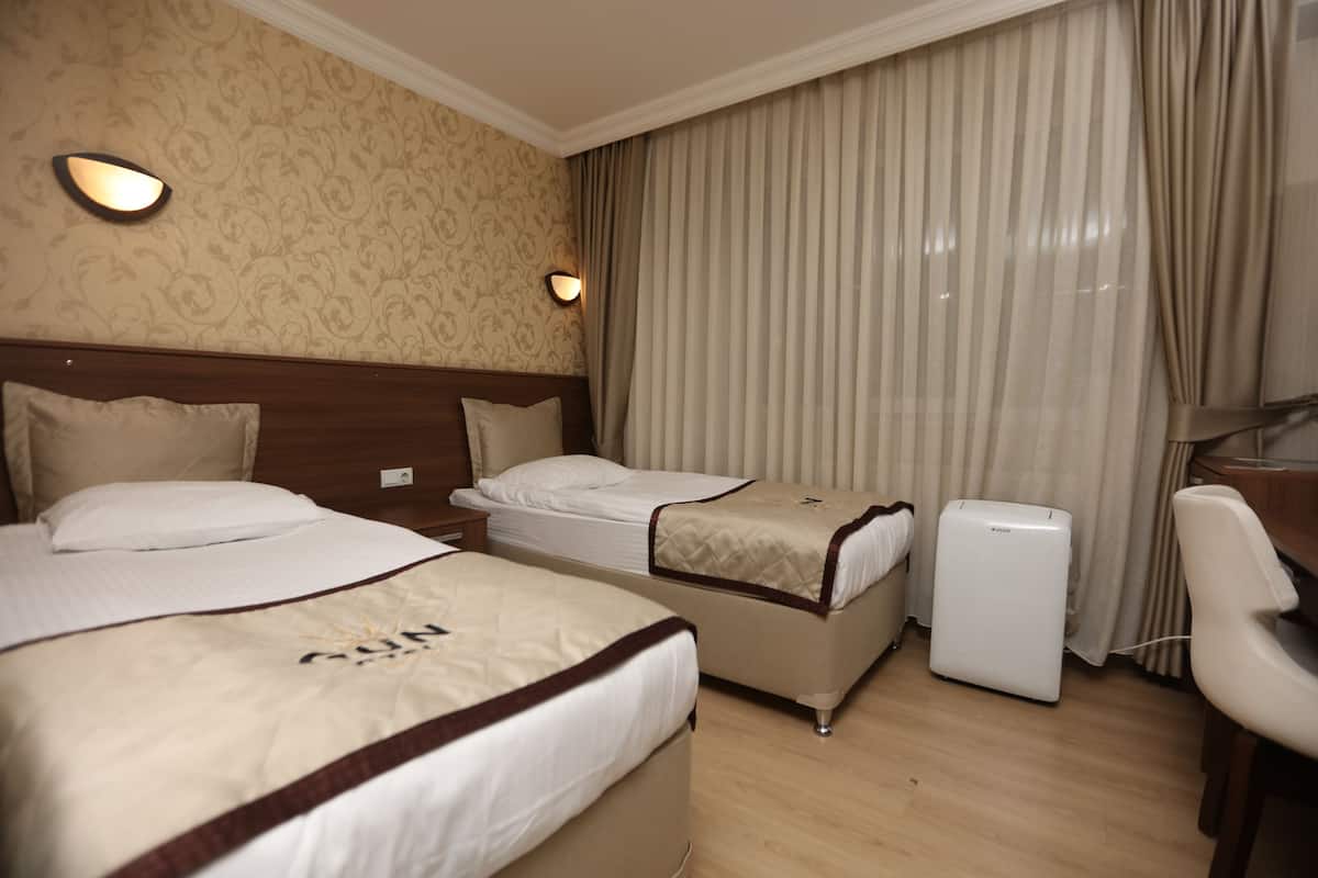 Ein Hotelzimmer mit zwei Betten, einem Schreibtisch, einem Stuhl und einem kleinen weißen Gerät.