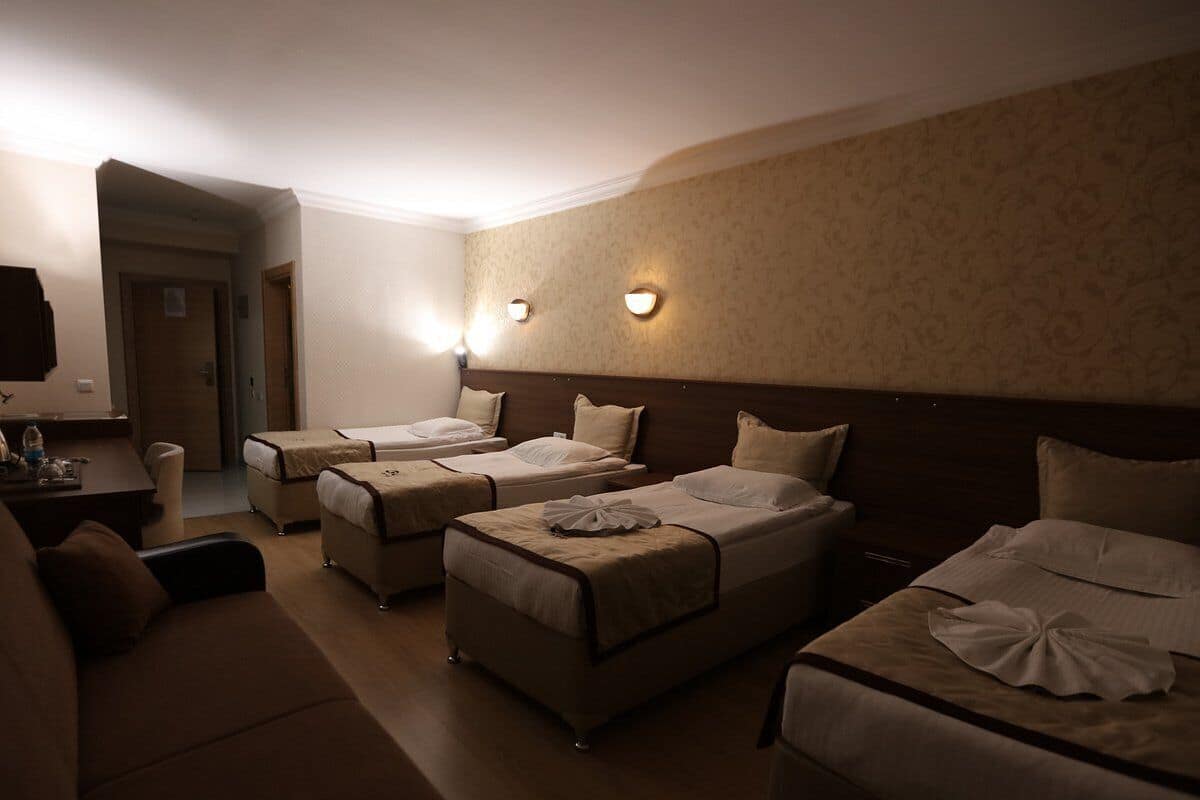 Ein Hotelzimmer mit zwei Einzelbetten, einem Schlafsofa, einem kleinen Tisch und einem Fernseher.