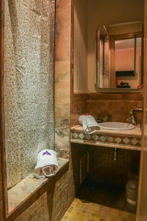 A bathroom with a shower, a sink, and a mirror.
