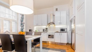 A modern kitchen with white cabinets, stainless steel appliances, and a dining area with a table and chairs. - Go Happy Home Apartment Mikonkatu 18 2 (Helsinki)