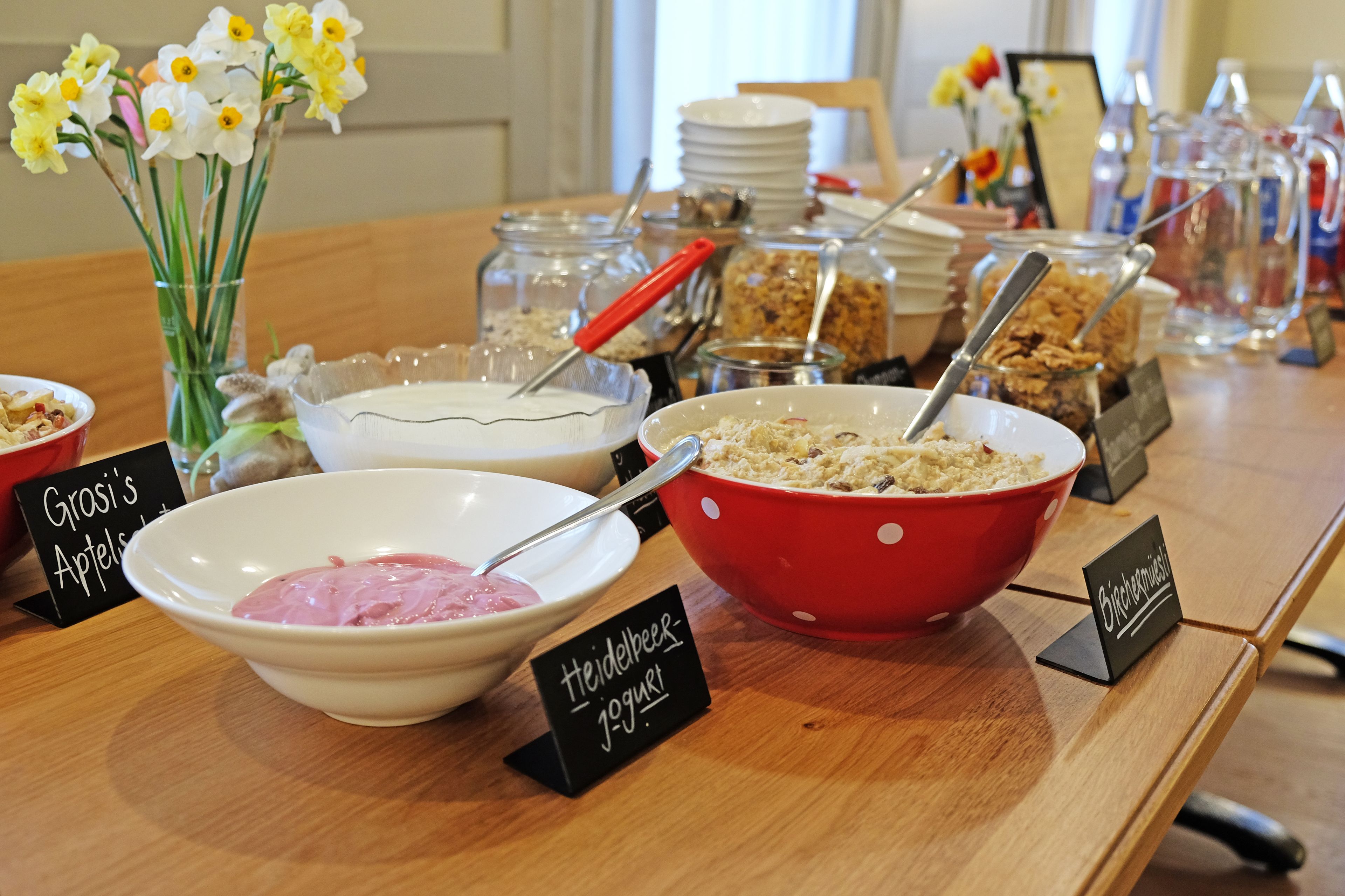 Una mesa de buffet con cuencos etiquetados de comida, incluyendo yogur y granola.