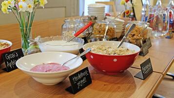 Una mesa de buffet con cuencos etiquetados de comida, incluyendo yogur y granola.