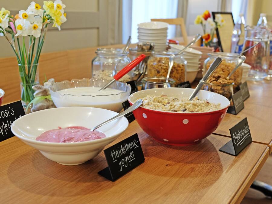 Una mesa de buffet con cuencos etiquetados de comida, incluyendo yogur y granola.