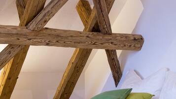 Ein Zimmer mit freiliegenden Holzbalken und einem Bett mit weißen und grünen Kissen.