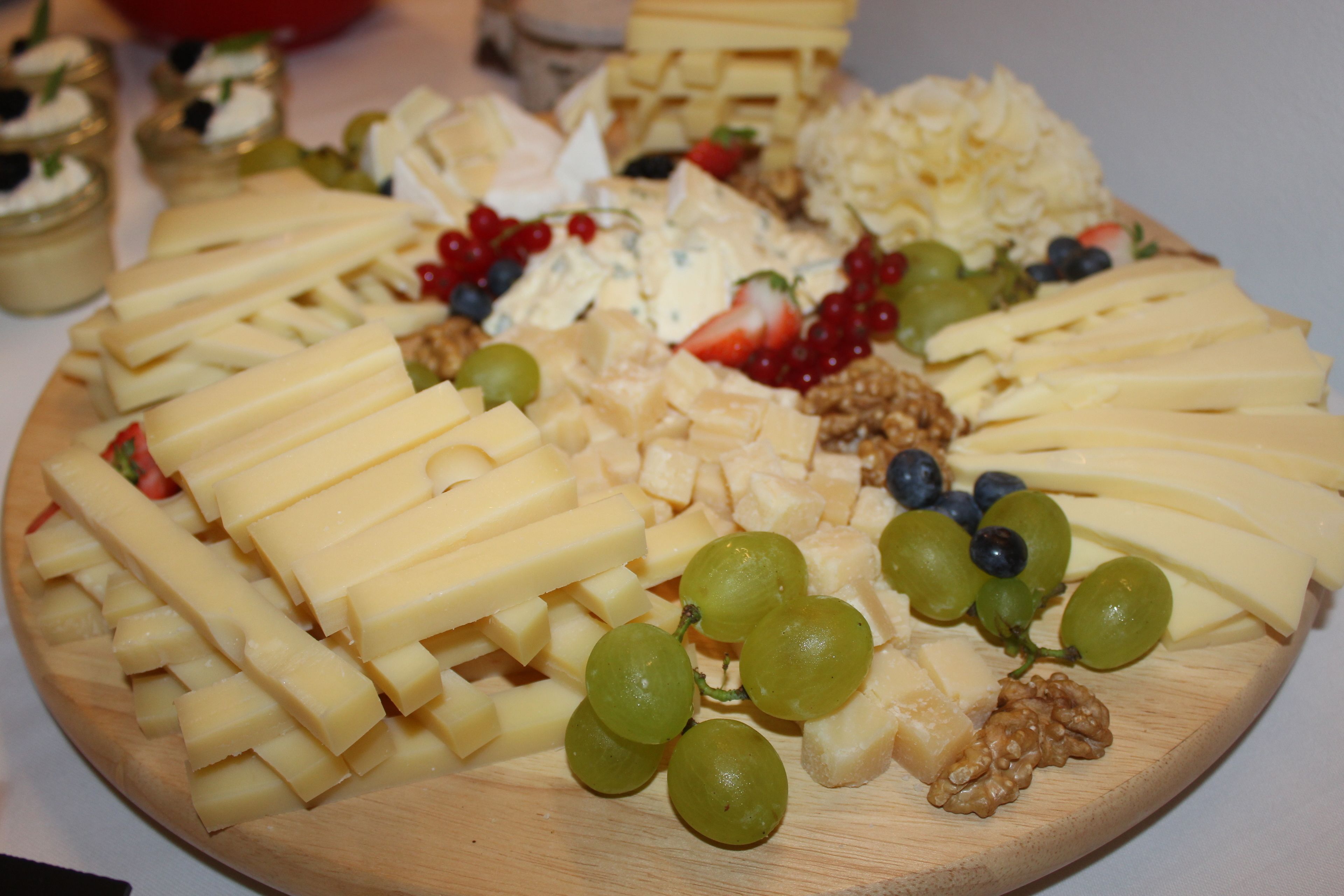 Una taula de fusta amb diferents formatges, raïm i fruits secs.