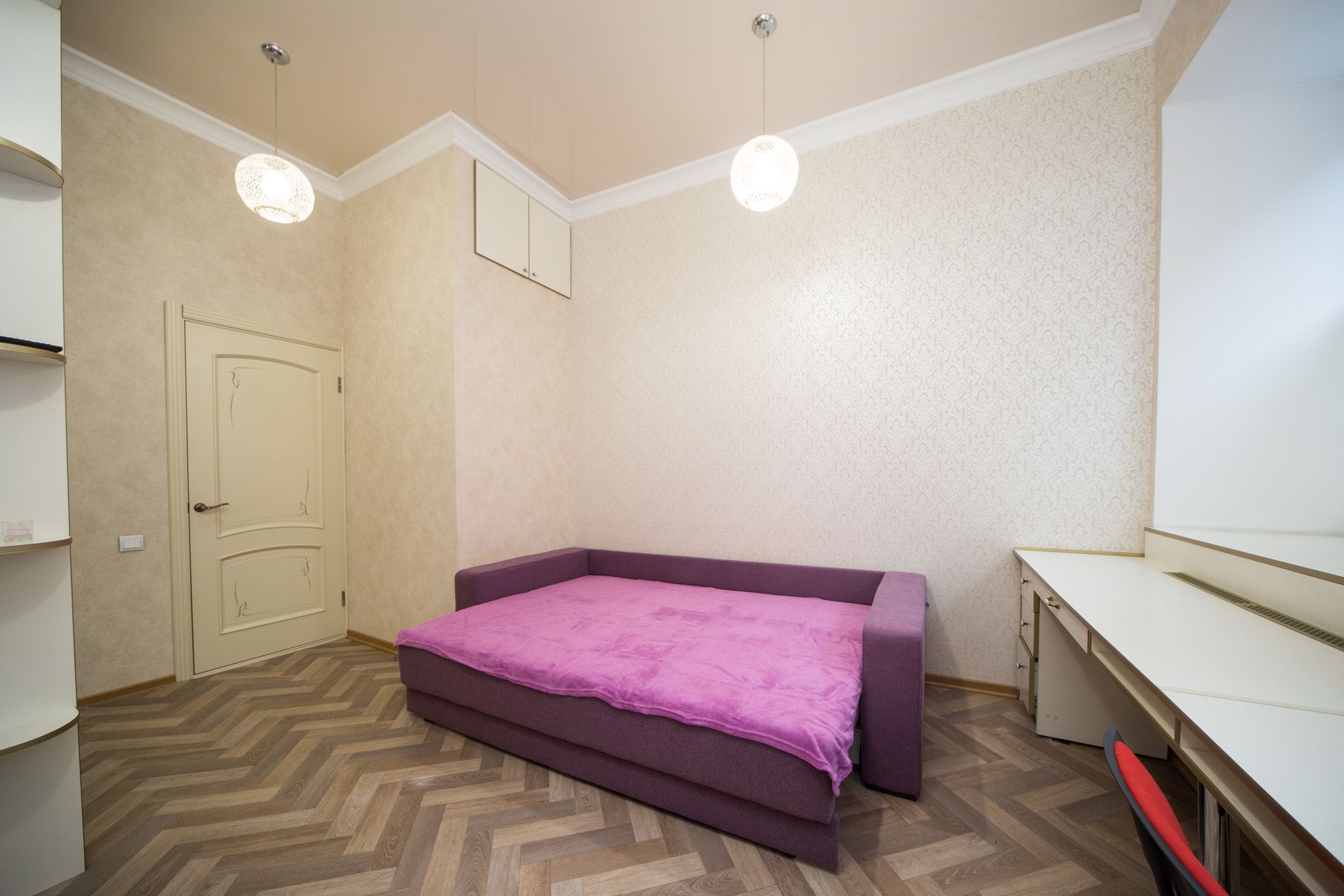 A bedroom with a bed, a desk, and a wardrobe.