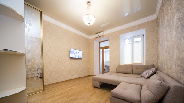 Una sala de estar con sofá, televisor y piso de madera.