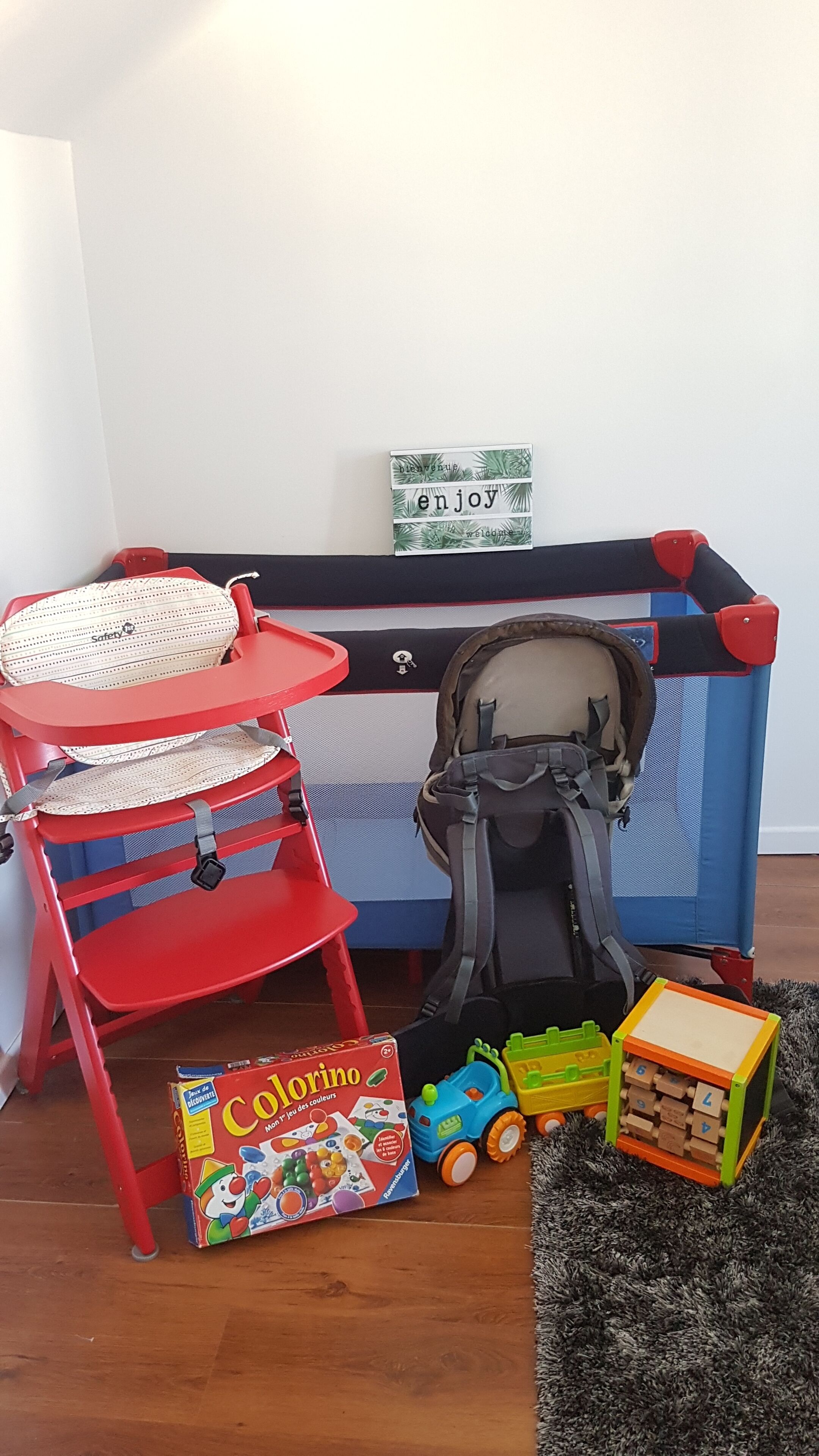 A child's play area with a red chair, a stroller, a toy train, and a coloring box.