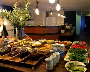 Un bufé con diferentes opciones de comida, entre ellas frutas, verduras y salsas.