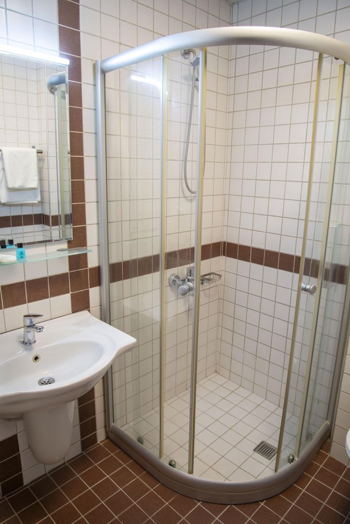 Een douchecel met glazen wanden, een wastafel en een spiegel.
