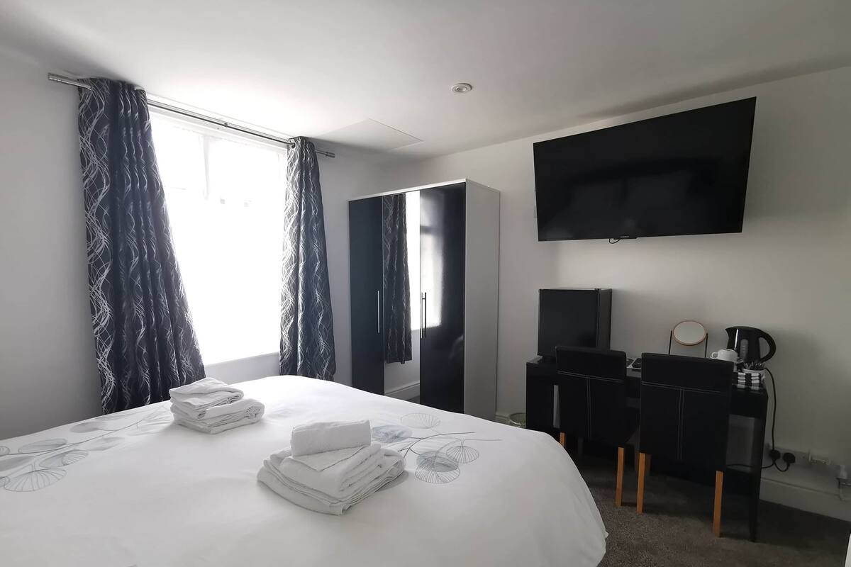 A hotel room with a bed, a desk with a computer, a TV, and a coffee maker.