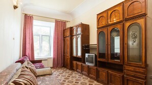 A living room with a sofa, a television, and wooden cabinets.