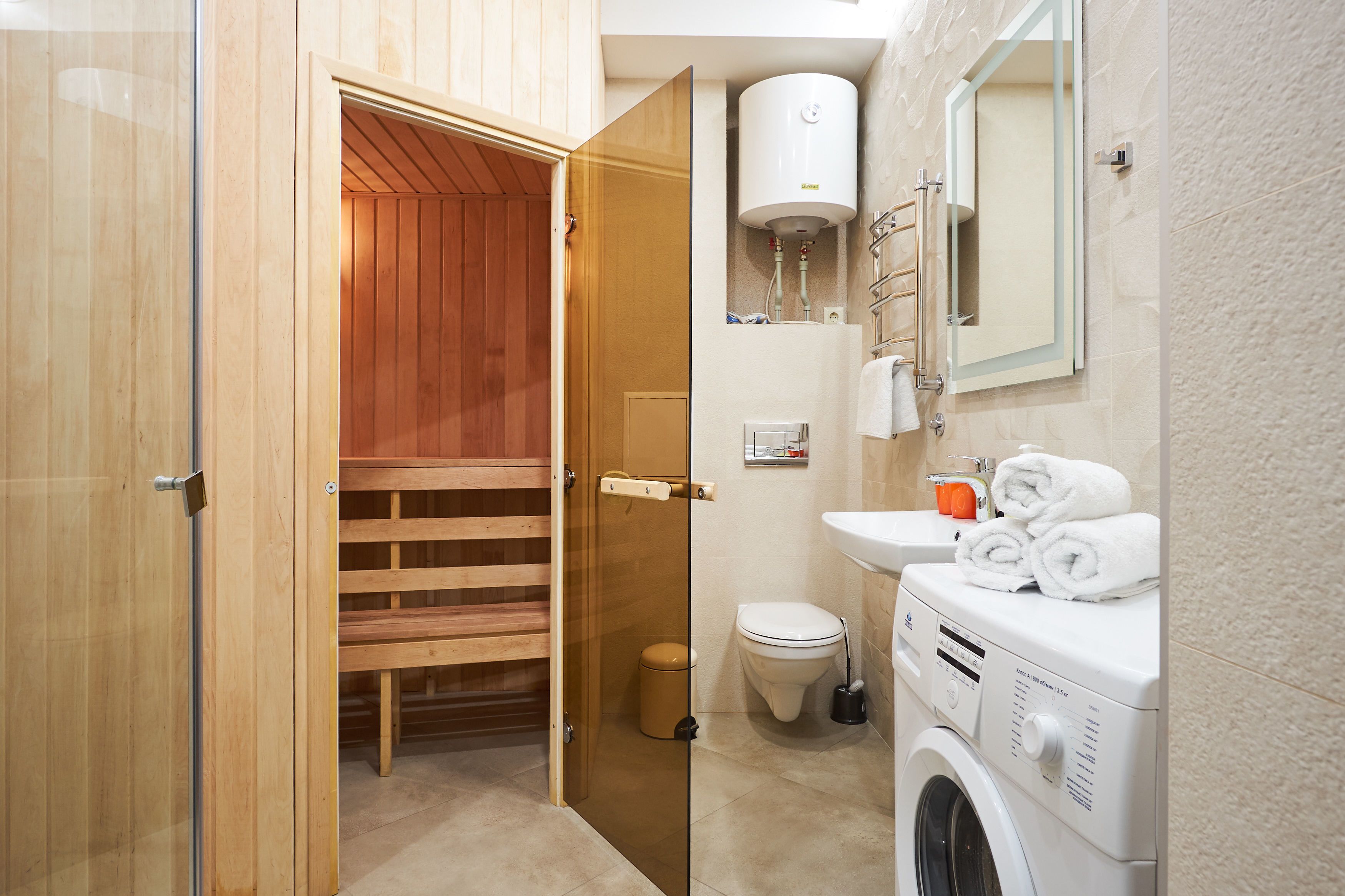 Une salle de bain moderne avec un sauna en bois, un lave-linge et des toilettes.