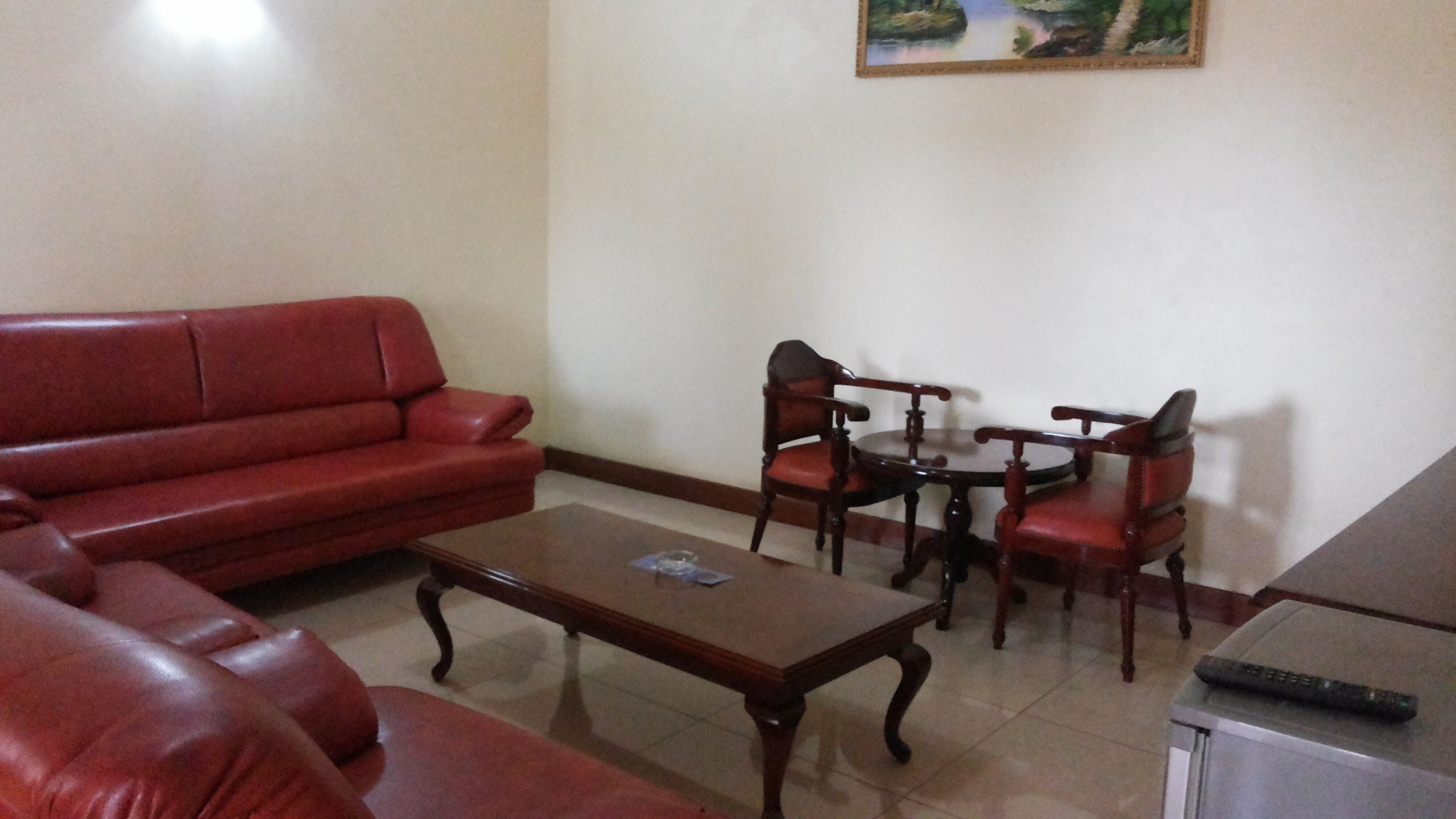 A living room with a red sofa, a wooden coffee table, and a dining set with chairs.