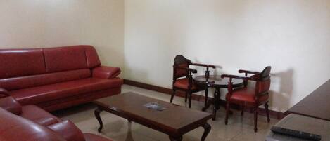 A living room with a red sofa, a wooden coffee table, and a dining set with chairs.