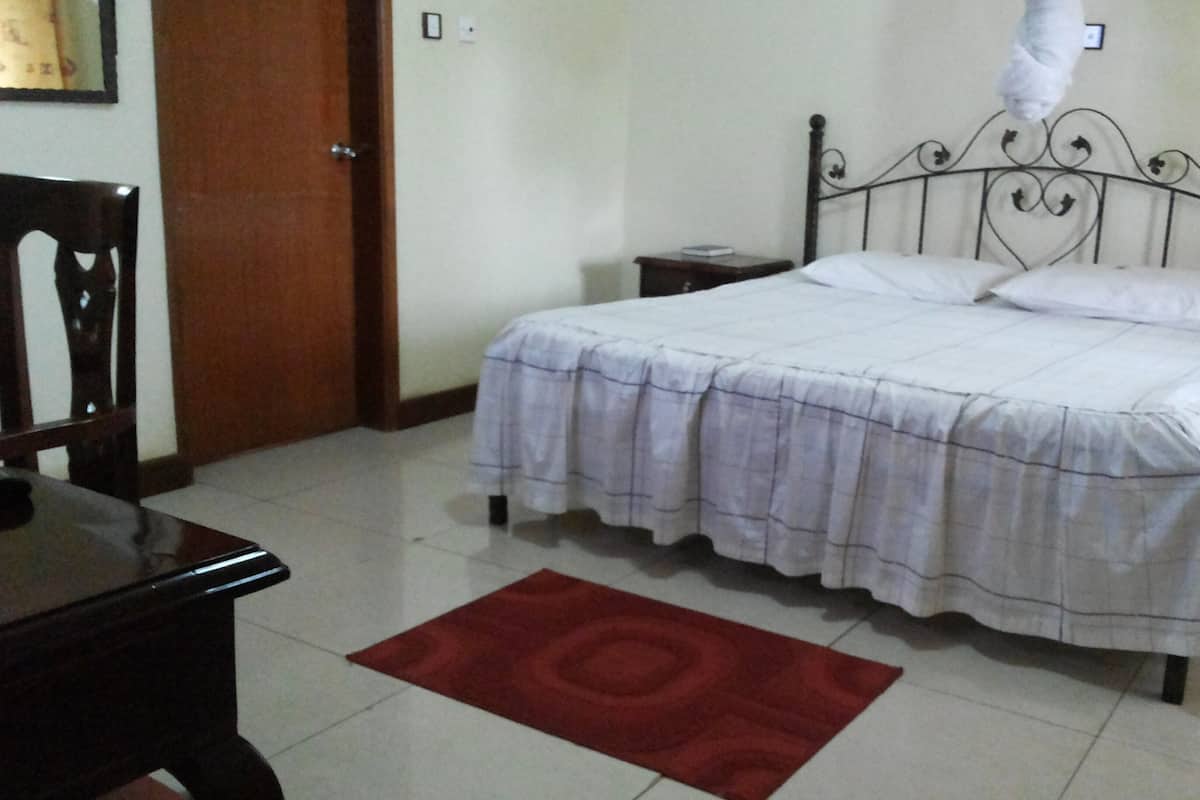 Un dormitorio con cama, mesita de noche, silla y alfombra roja.
