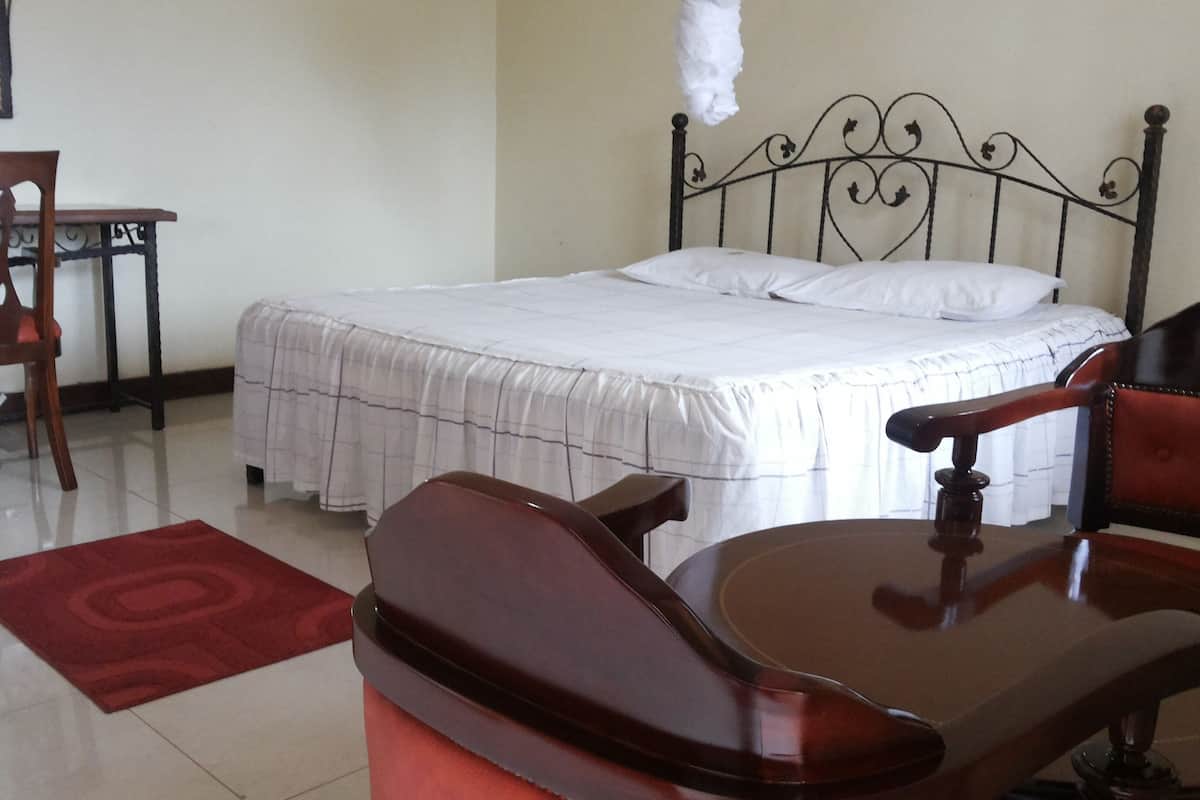 Un dormitorio con cama, escritorio y dos sillas.