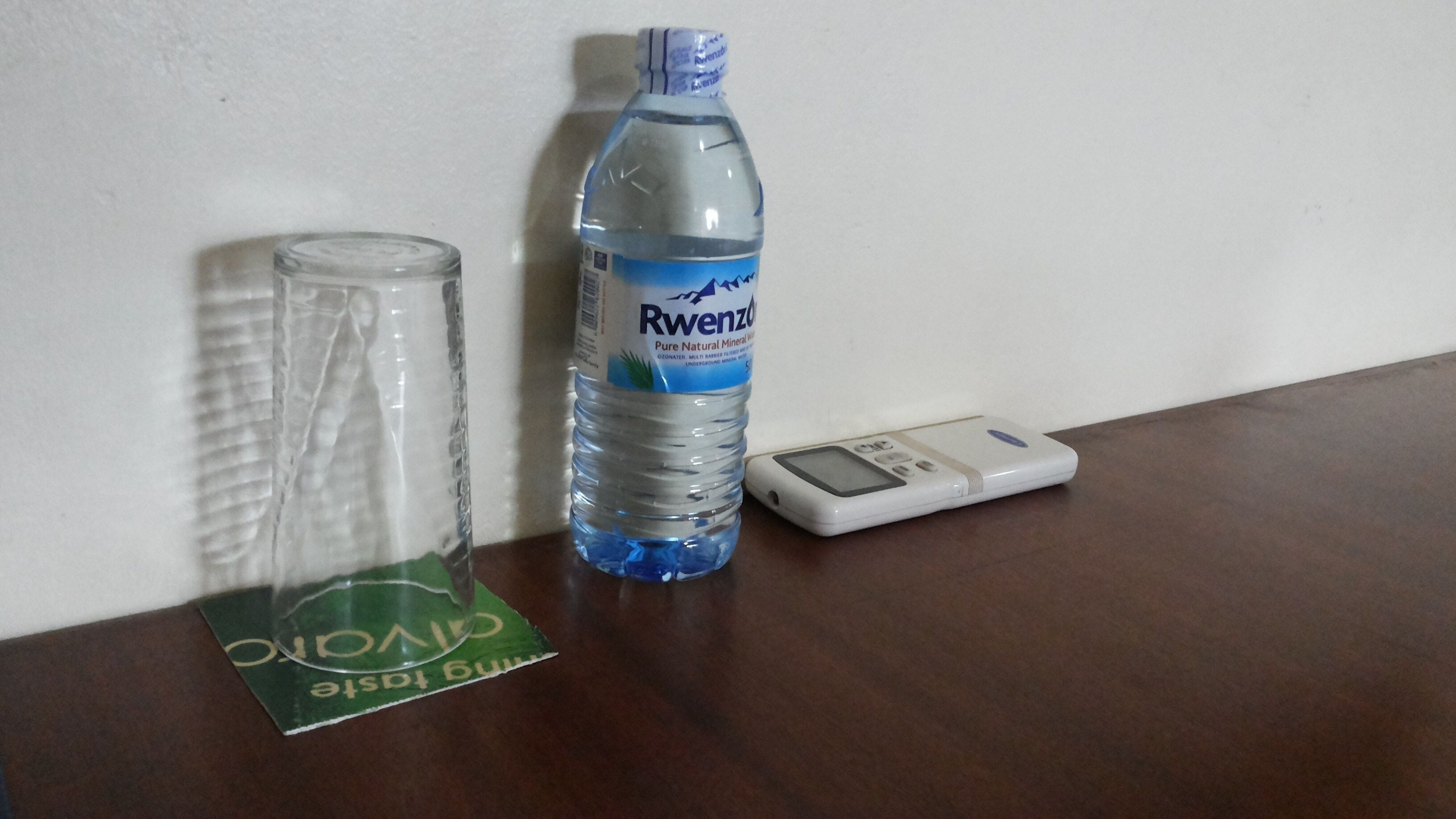 A bottle of Rwenzu water, a glass, and a digital scale on a wooden table.