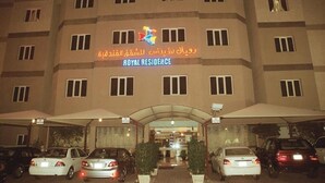 A hotel entrance with a sign reading "ROYAL RESIDENCE" and multiple cars parked in front. - Royal Residence Hotel (Kuwait City)