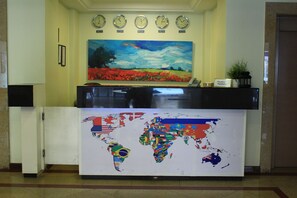 A reception desk with a world map mural, clocks displaying different time zones, and a reception sign.