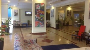 A lobby with a sofa, a table, and a pillar with a colorful mural. - Royal Residence Hotel (Kuwait City)