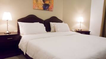 A hotel room with a large bed, two bedside tables with lamps, and a painting on the wall.