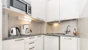 A compact kitchen with white cabinets, a microwave, a coffee maker, and a dishwasher. - Go Happy Home Apt Vuorimiehenkatu 14 (Helsinki)