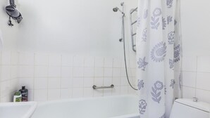 A bathroom with a bathtub, a shower, and a toilet. - Go Happy Home Apt Vuorimiehenkatu 14 (Helsinki)