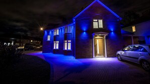 A two-story house with a brick facade and blue exterior lighting. - Goldbeaters House (Edgware)