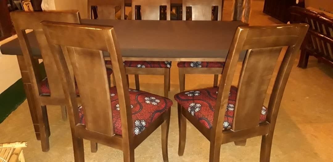 Una mesa de comedor con seis sillas de madera, cada una con un cojín estampado.