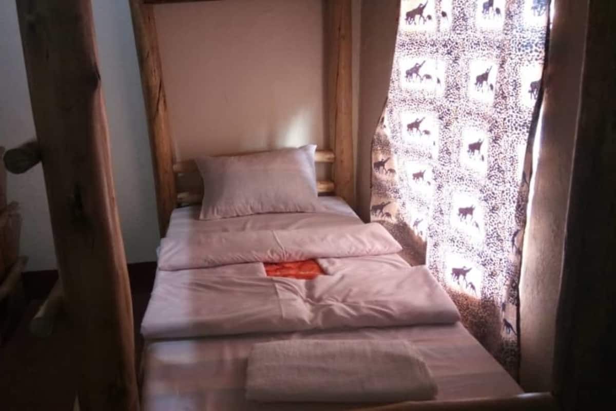 A single bed with a wooden headboard, a pillow, and a blanket.
