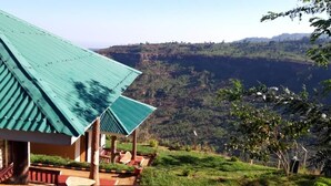 A building with a green roof, a covered outdoor seating area, and a view of a mountainous landscape. - Rafiki Lodge Sipi (Sipi)