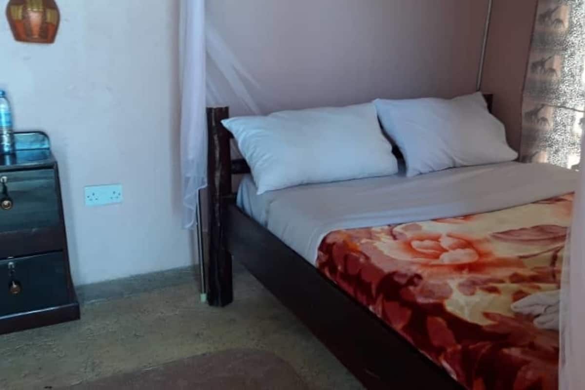 A bedroom with a bed, a nightstand, and a water bottle on the nightstand.