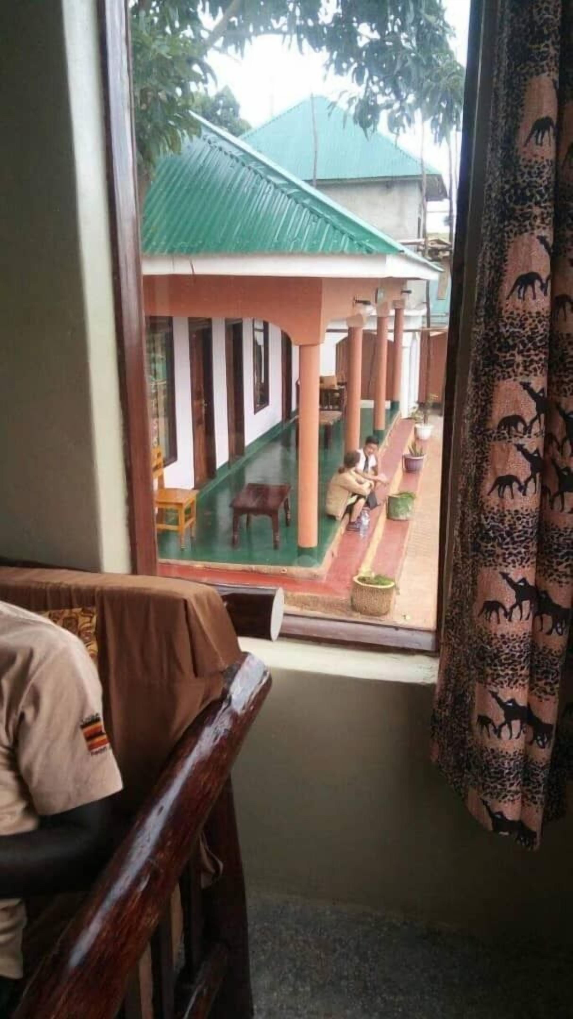 A room with a view of an outdoor area featuring a covered walkway, a table, and chairs.