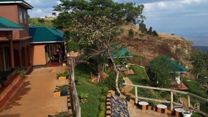 A building with a green roof, a paved pathway, and a landscaped garden with a patterned walkway. - Rafiki Lodge Sipi (Sipi)
