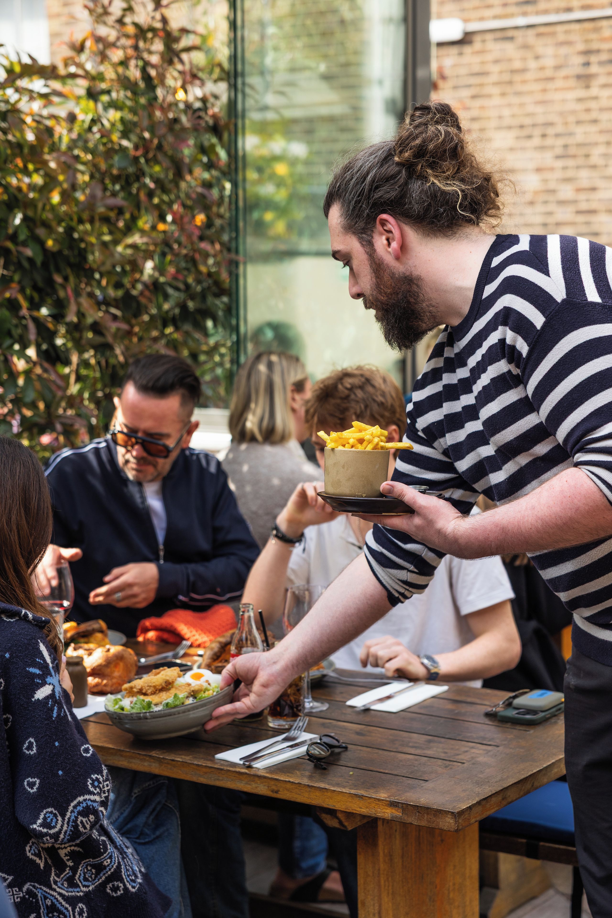 A dining table with food and drinks, surrounded by people.