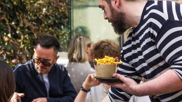 A dining table with food and drinks, surrounded by people.