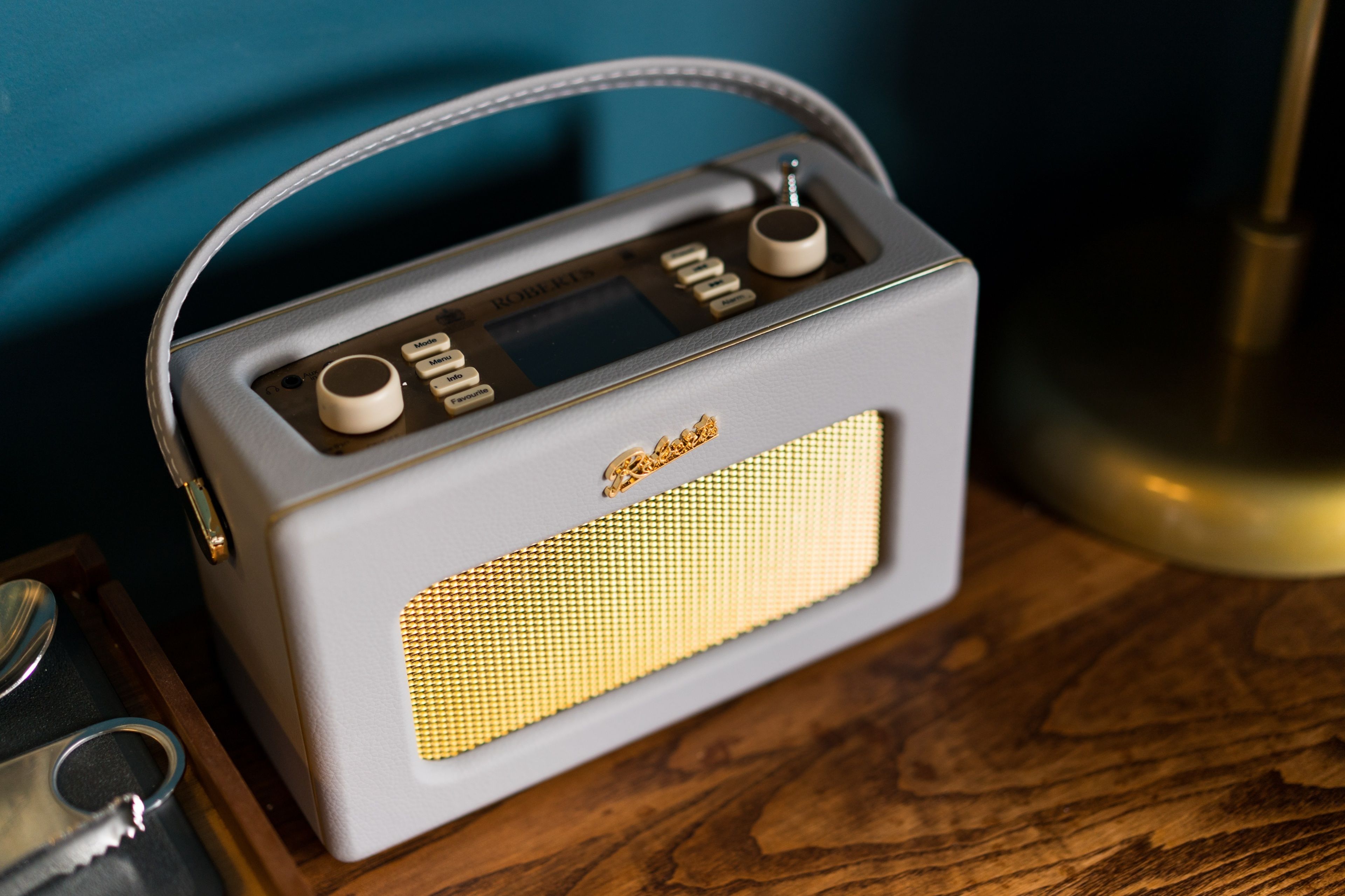 A vintage radio with a handle, placed on a wooden surface.