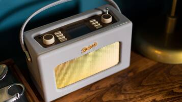 A vintage radio with a handle, placed on a wooden surface.