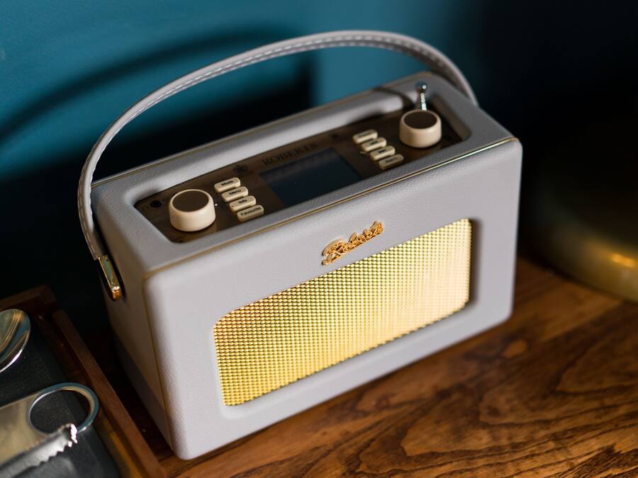 A vintage radio with a handle, placed on a wooden surface.