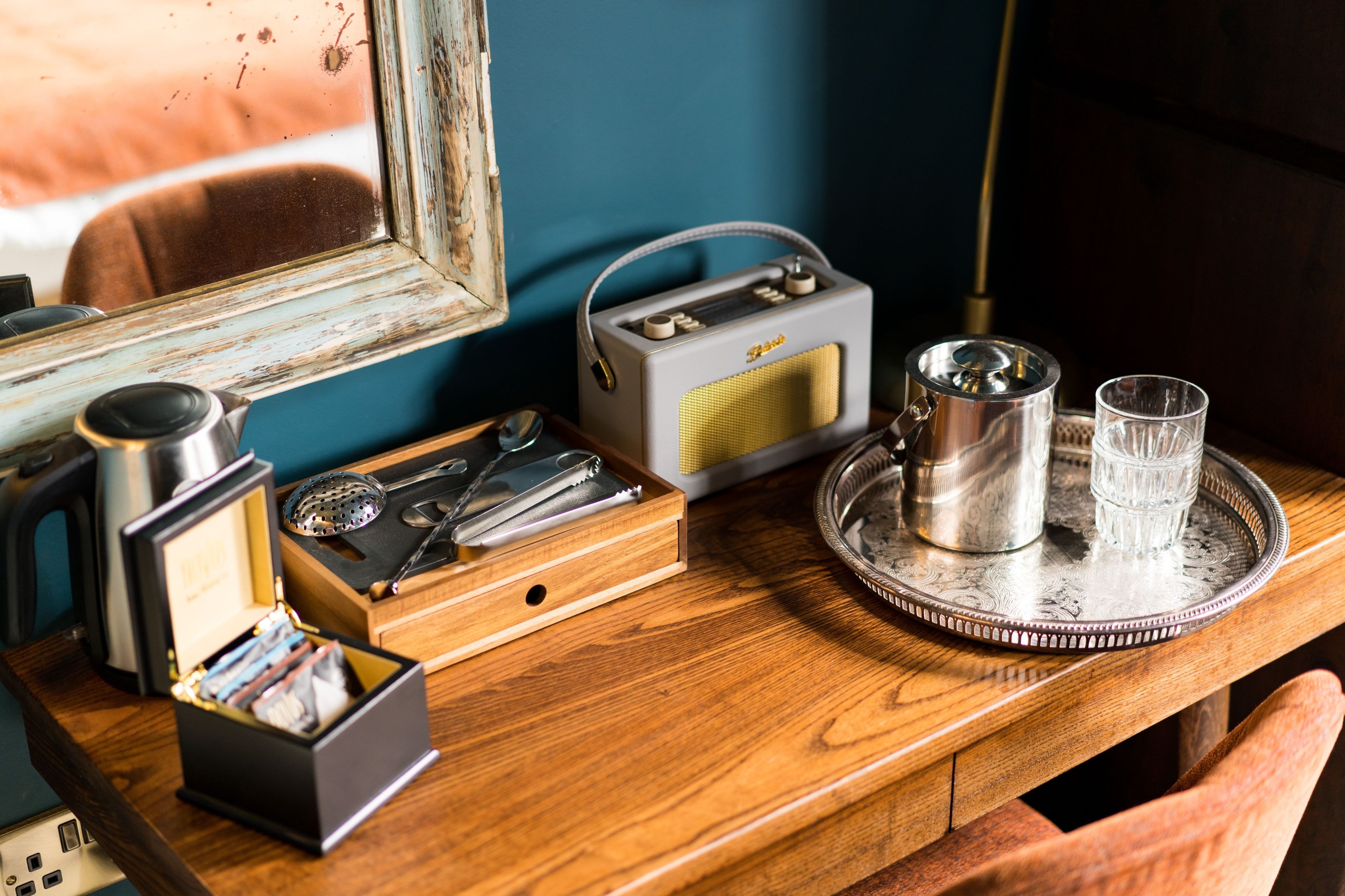 A wooden table with a radio, a thermos, a glass, and a tray with a teapot.