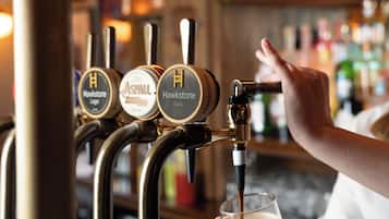 A bar with a tap labeled 'Hawstone Black' and a hand pouring a drink into a glass.
