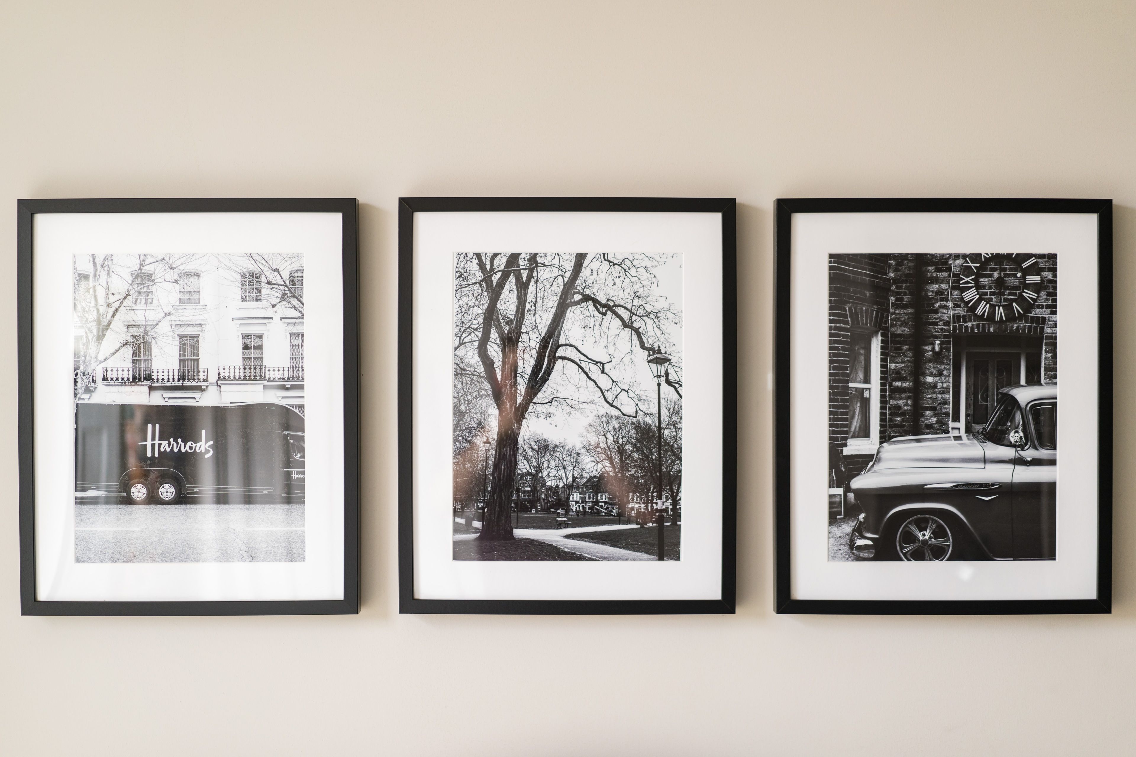 Tres fotografías en blanco y negro enmarcadas que muestran escenas urbanas, incluyendo un coche antiguo y la fachada de un edificio.
