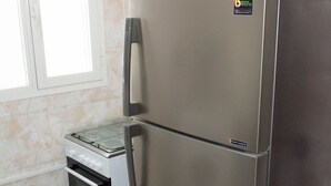 Ett kylskåp i rostfritt stål med ett frysfack, en inbyggd ugn och en digital display.
