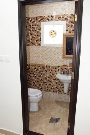 Un baño con inodoro, lavamanos y pared decorada con azulejos.