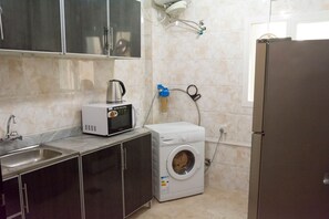 Una cocina compacta equipada con microondas, lavadora y refrigerador.