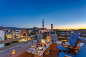 A rooftop terrace with a table set for dining, seating, and a view of the cityscape and mountains. - Chania Escapes Old Town-Casa Barchetta- Adults Only (Chania)