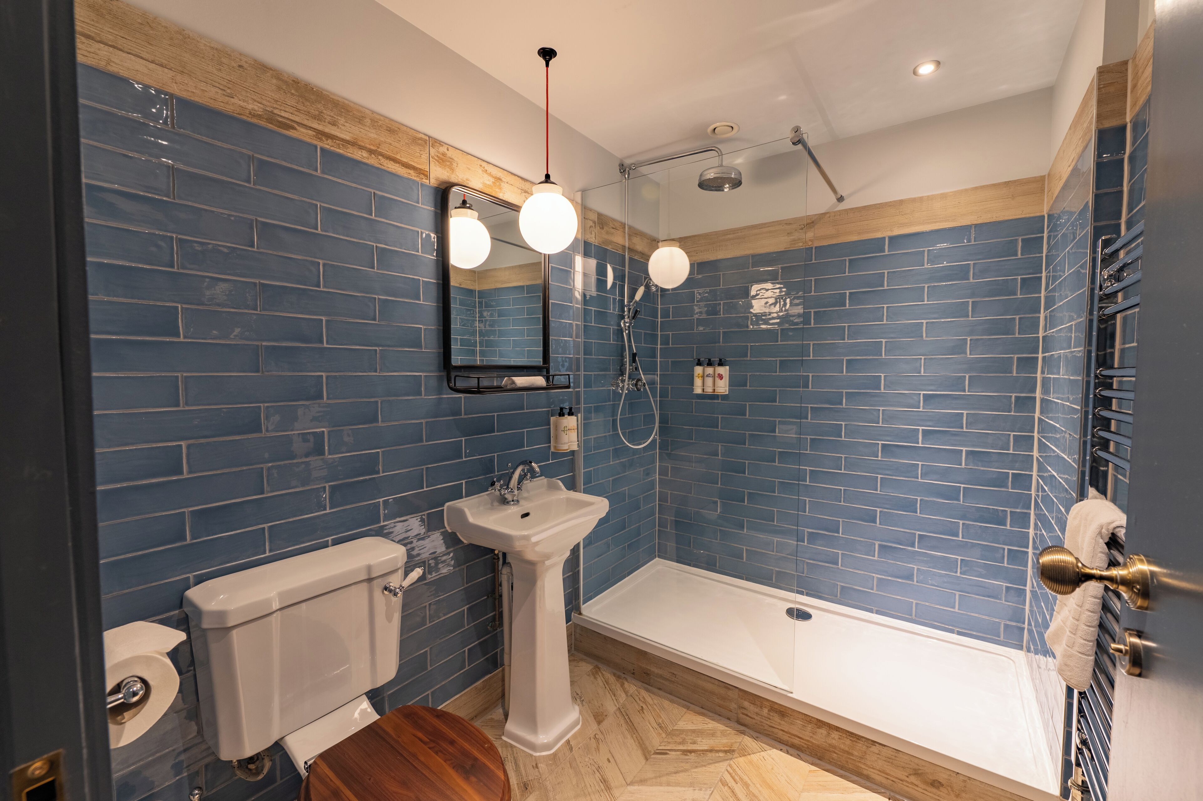 Un baño con paredes de azulejos azules, un lavabo blanco, un inodoro y una bañera.