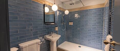 Un baño con paredes de azulejos azules, un lavabo blanco, un inodoro y una bañera.